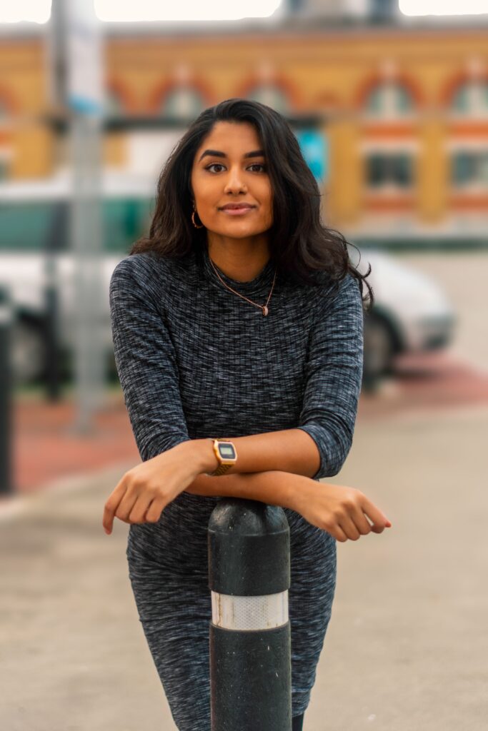 Services Stylish woman in a grey dress posing outdoors in London, exuding elegance and charm.